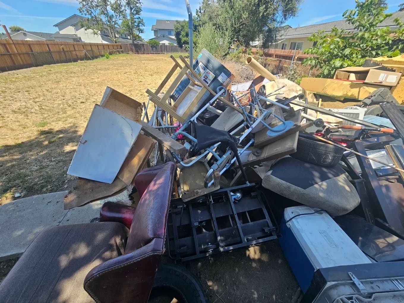 A real Junk Magik backyard cleanout, with a sunny pile of chairs, broken furniture and a cooler waiting to be loaded