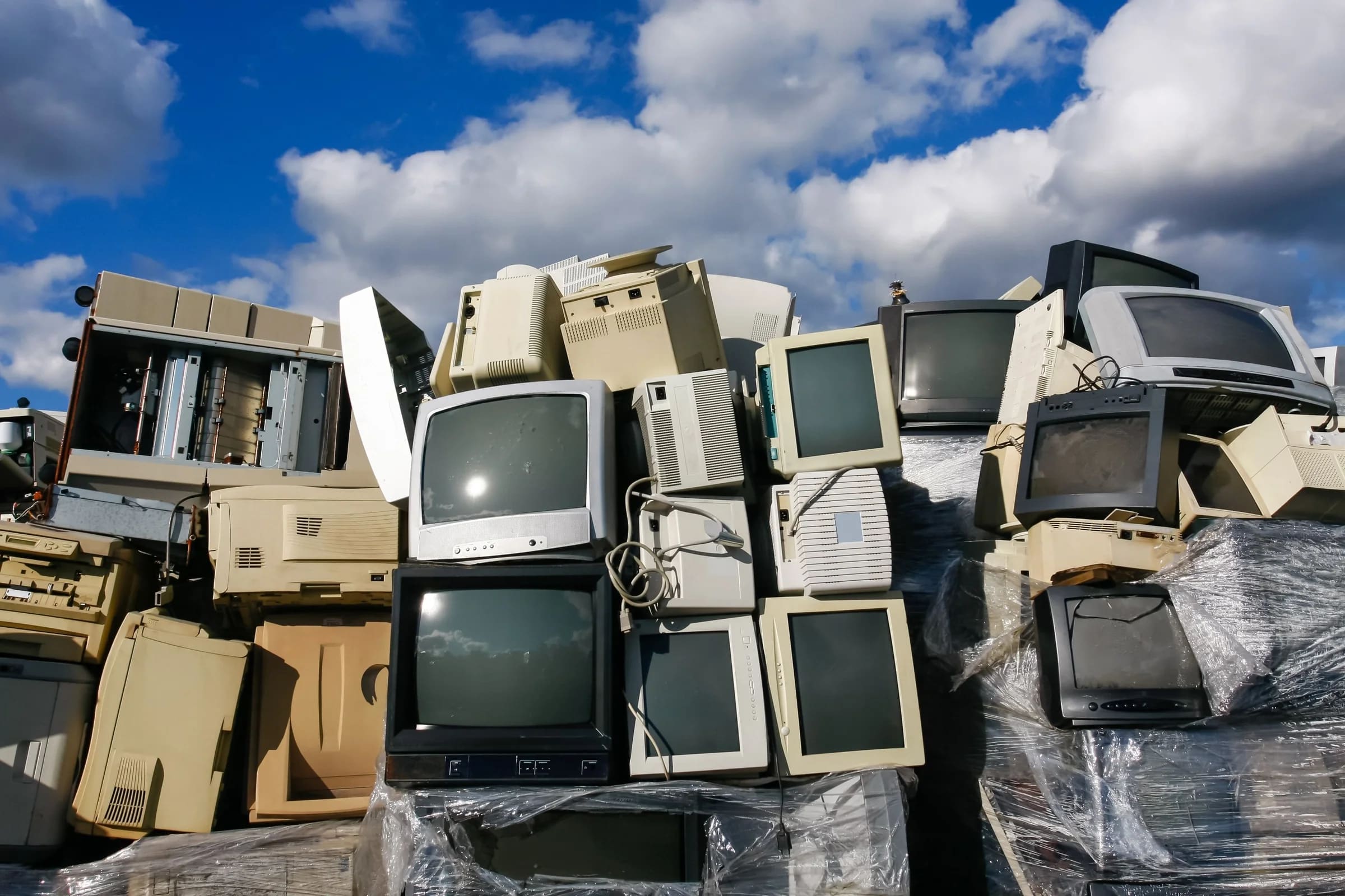 A wall of outdated televisions, CRT monitors and office printers piled up and waiting to be recycled